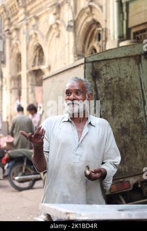 A vertical shot of a Pakistani old male with a white beard in a kurta on the street Stock Photo