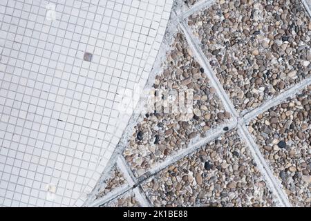 Half of small white and dirty squared ceramic tiles and old brown pebble stone floor texture and pattern, retro mosaic, urban rough textured surface, Stock Photo