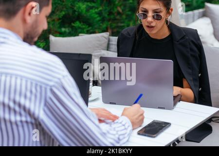 Two business guys are working on their business project seriously, online, in a cafe bar, on a beautiful day Stock Photo