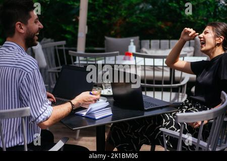 Young business couple are telling jokes and laughing while they are talking about their business project Stock Photo