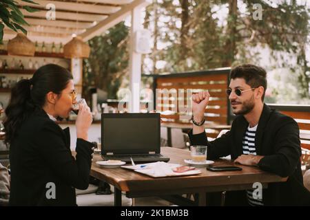 Beautiful business couple drinking coffee and talking while sitting at the cafe Stock Photo