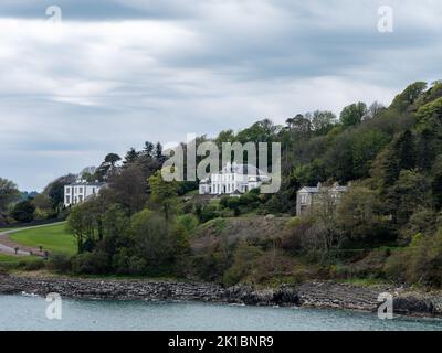 A hill on the shore of the bay. Several buildings and trees on the hill. Glandore is a village in the south of Ireland. Beautiful clouds in the sky, d Stock Photo