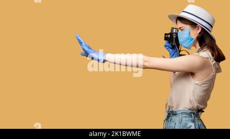 Travel photography. Covid-19 restriction. Keep distance. Capture memories. Woman in protective mask gloves taking photo retro camera putting out hand Stock Photo
