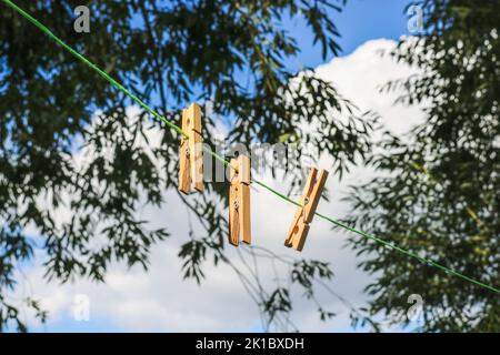 Clothespins on a rope against the background of green foliage and the sky. Stock Photo