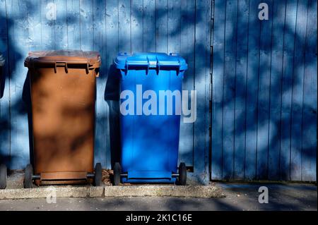 Wheelie bin colour blue, purple and black for refuge collection outside house in a row Stock Photo