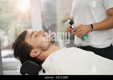 Chill brunette guy laying down in barbershop chair Stock Photo