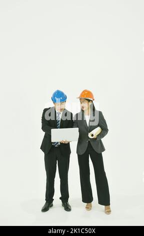 architect man and woman wearing colorful helmet diccusing for work in whitre background Stock Photo