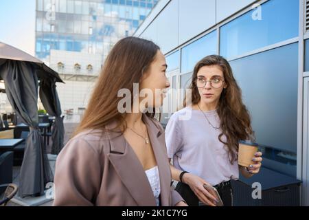 Two women are having a coffee break outdoors near office Stock Photo