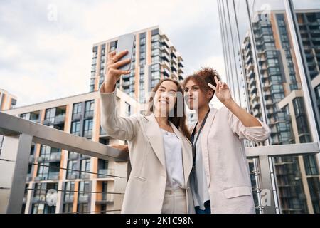 Joyful office employees taking selfies on outdoor balcony Stock Photo
