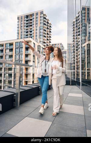 Company employee pointing at something to female colleague during stroll Stock Photo