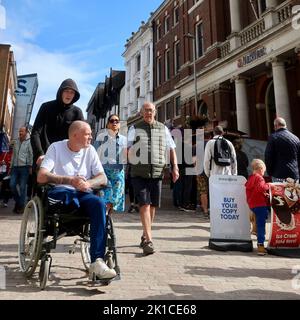 Ipswich, Suffolk, UK - 17 September 2022 : A man in a wheelchair is pushed through the town centre by a younger man. His right leg is missing. Stock Photo