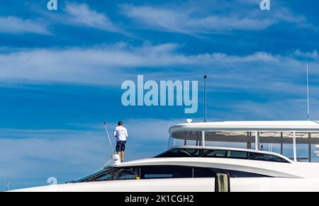 Deck hand cleaning the top of an expensive motor yacht Stock Photo