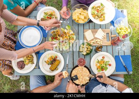 Top view of people serving food and drinks in a wooden teal table. Getting together concept. Stock Photo