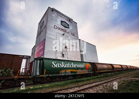 A low-angle view of the Grain Elevator in Chamberlain Saskatchewan in Canada with a train passing in front Stock Photo