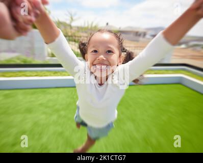 Girl child happy, parent pov of fun outdoor in garden and parent hand swinging kid by arms in circle movement. Family play game on green grass Stock Photo