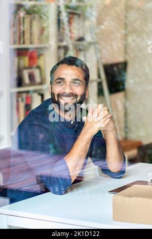 Successful happy indian business man looking away at work. View through glass Stock Photo