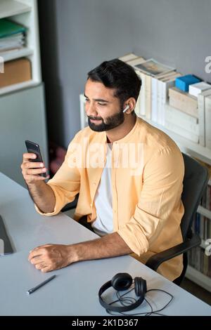 Indian business man having video call at work using mobile phone, vertical. Stock Photo
