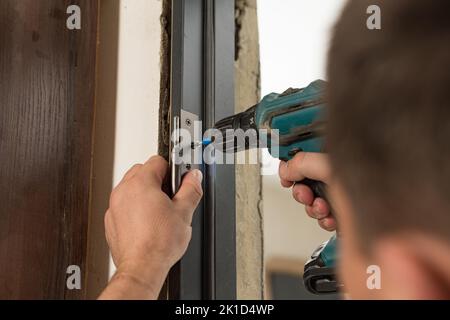 Installing a stainless hinge on an interior door, screwing a screw in a detailed plan, installing an interior door. Stock Photo