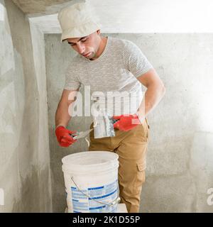 The master works with lime plaster, leveling the wall with a spatula and lime plaster, repairing work on leveling the walls. Stock Photo