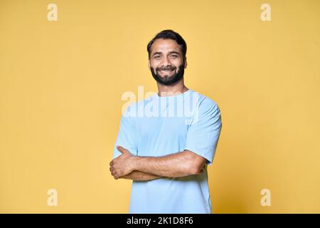 Smiling confident bearded indian man standing isolated on yellow background. Stock Photo
