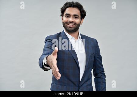 Smiling arab business man extending hand for handshake isolated on beige. Stock Photo