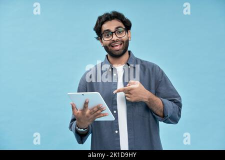 Excited arab student pointing at digital tablet presenting new online product. Stock Photo