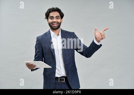 Happy arab indian businessman pointing holding tablet presenting online product. Stock Photo