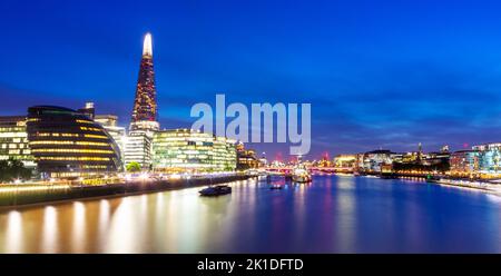 Panoramic view,looking south west,the Shard,HMS Belfast and other buildings along London South Bank, illuminated against inky blue summer sky. Stock Photo