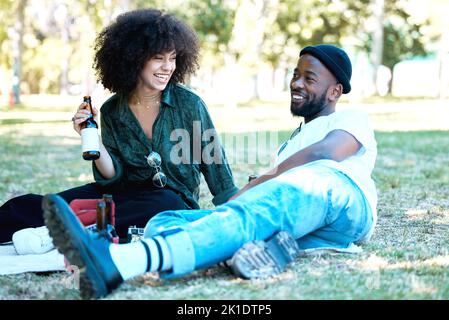 Interracial couple in nature park together, man and woman relax with drink on grass and happiness for people on picnic date outside. Happy black Stock Photo