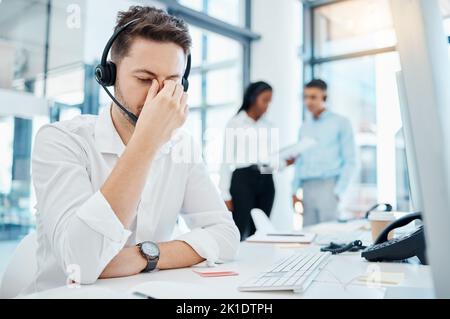 Call center, headache and burnout of a man in customer service or support with eye strain at the office. Business male or employee in telemarketing Stock Photo