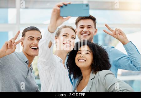Business people talking selfie on mobile phone at work, peace hand sign and happiness during team collaboration in an office. Manager doing teamwork Stock Photo