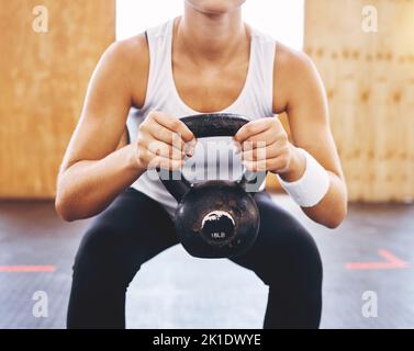 Health, energy and training with athlete woman weightlifting with kettlebell at fitness center or gym. Strong female doing power exercise and Stock Photo