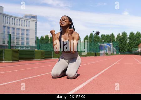 African American female athlete feels happy after running long distance on track at sports ground Stock Photo