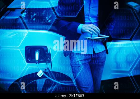 Black background with shiny hexagons against businessman using digital tablet while charging electric car Stock Photo