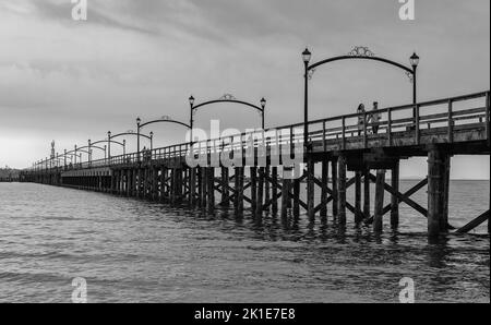 Wooden pier at White Rock, BC, Canada extends diagonally into image. City of White Rock Pier at overcast cloudy day, BC, Canada. Travel photo, copy sp Stock Photo