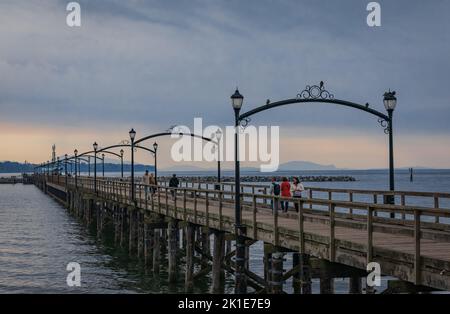 Wooden pier at White Rock, BC, Canada extends diagonally into image. City of White Rock Pier at overcast cloudy day, BC, Canada. Travel photo, copy sp Stock Photo