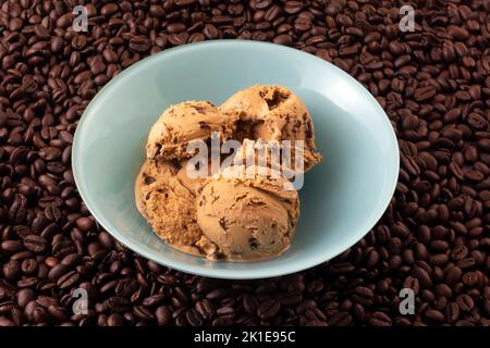 Coffee ice cream with espresso chocolate chips in blue dessert bowl on background of roasted coffee beans Stock Photo