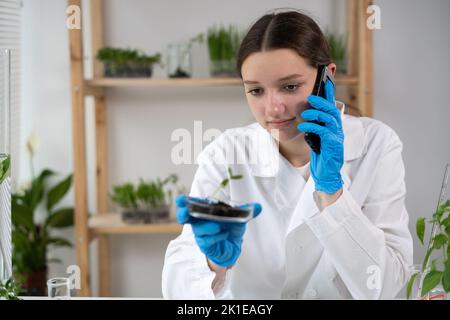 Scientist Talking on Phone in Agronomy Laboratory with young plants. Analysis of growing GMO food Stock Photo