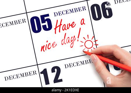 5th day of December. The hand writing the text Have a nice day and drawing the sun on the calendar date December 5. Save the date. Winter month, day o Stock Photo