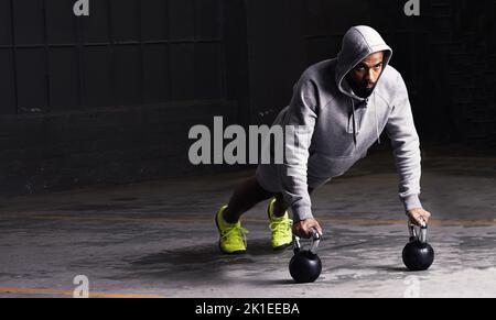 Perfect form. a young man doing push-ups with kettle bell weights. Stock Photo