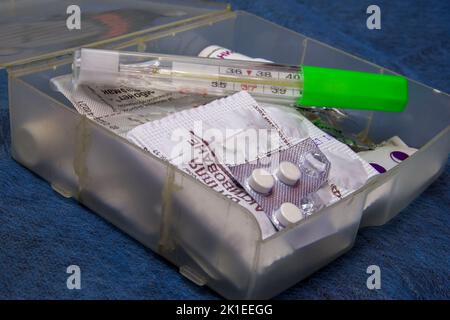 a first aid kit with a thermometer on a blue medical cloth Stock Photo