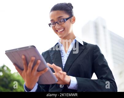Free wifi - a perk of the city. A happy young businesswoman using her digital tablet outdoors. Stock Photo