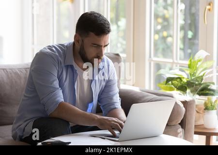 Focused millennial freelancer man working from home, typing on laptop Stock Photo