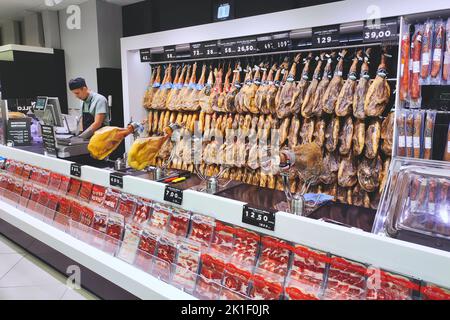 June 08 2022 - Seville, Spain: Hanging cured hams on the wall in a Spanish supermarket Stock Photo