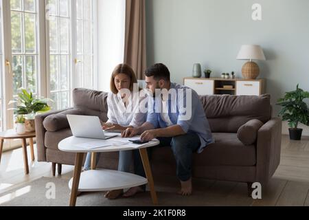 Serious millennial husband and wife discussing family expenses Stock Photo