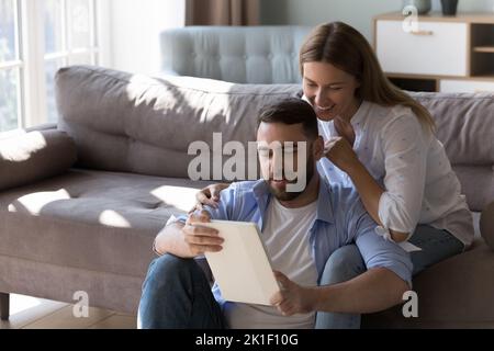 Happy 30s husband and wife using tablet computer Stock Photo