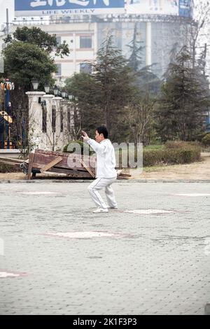 Senior Asian man dressed in white practices tai 'chi exercises outdoors, Shanghai, China, Asia Stock Photo