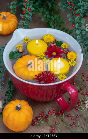 decoration with pumpkins, floating candles and flowers in porcelain bowl Stock Photo