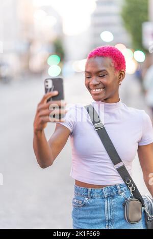 African woman with pink hair taking a selfie Stock Photo
