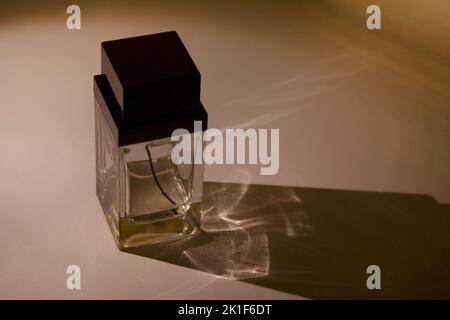 Glass perfume bottle container with a long shadow on dark background Stock Photo